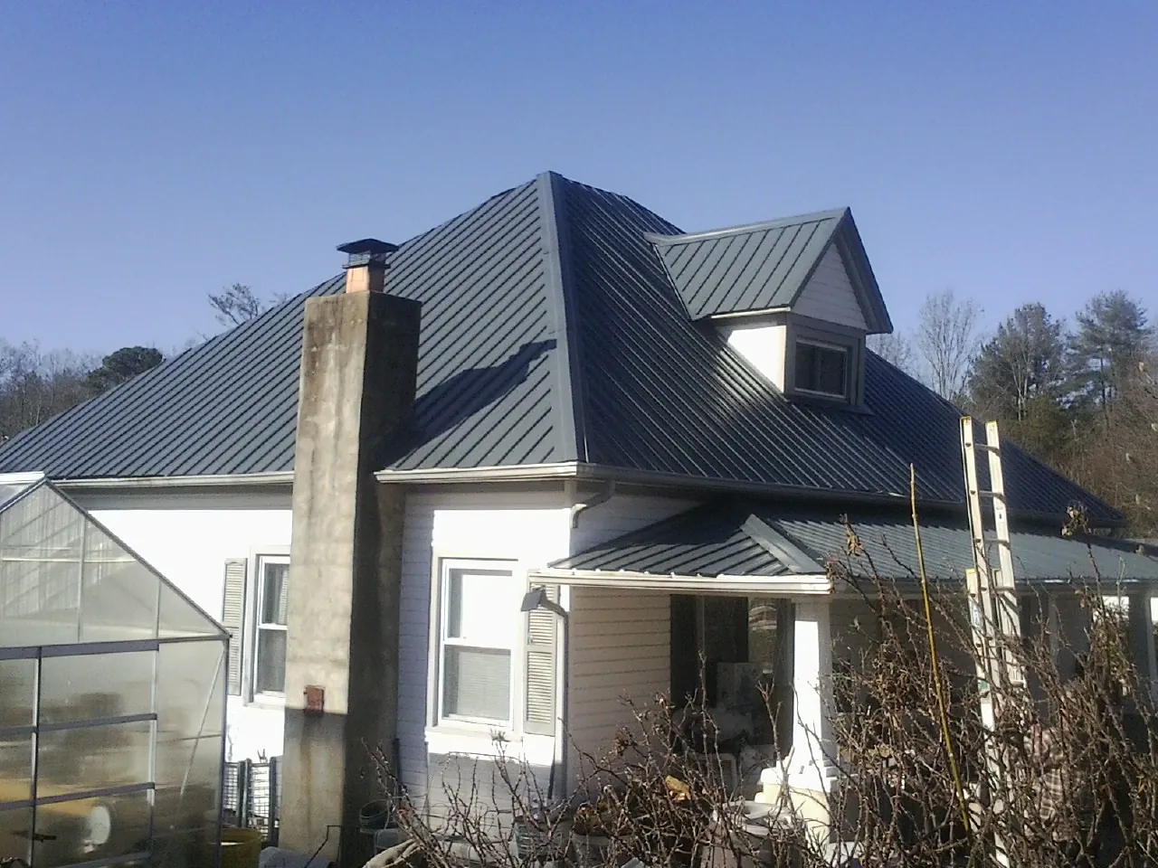 Dark blue standing seam metal roof on a white farmhouse with dormer — Slate & Tile Roof Repair by Roofing Brothers in Uhrichsville