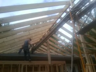 Rafters going up over a new addition with a worker on the wall in Uhrichsville