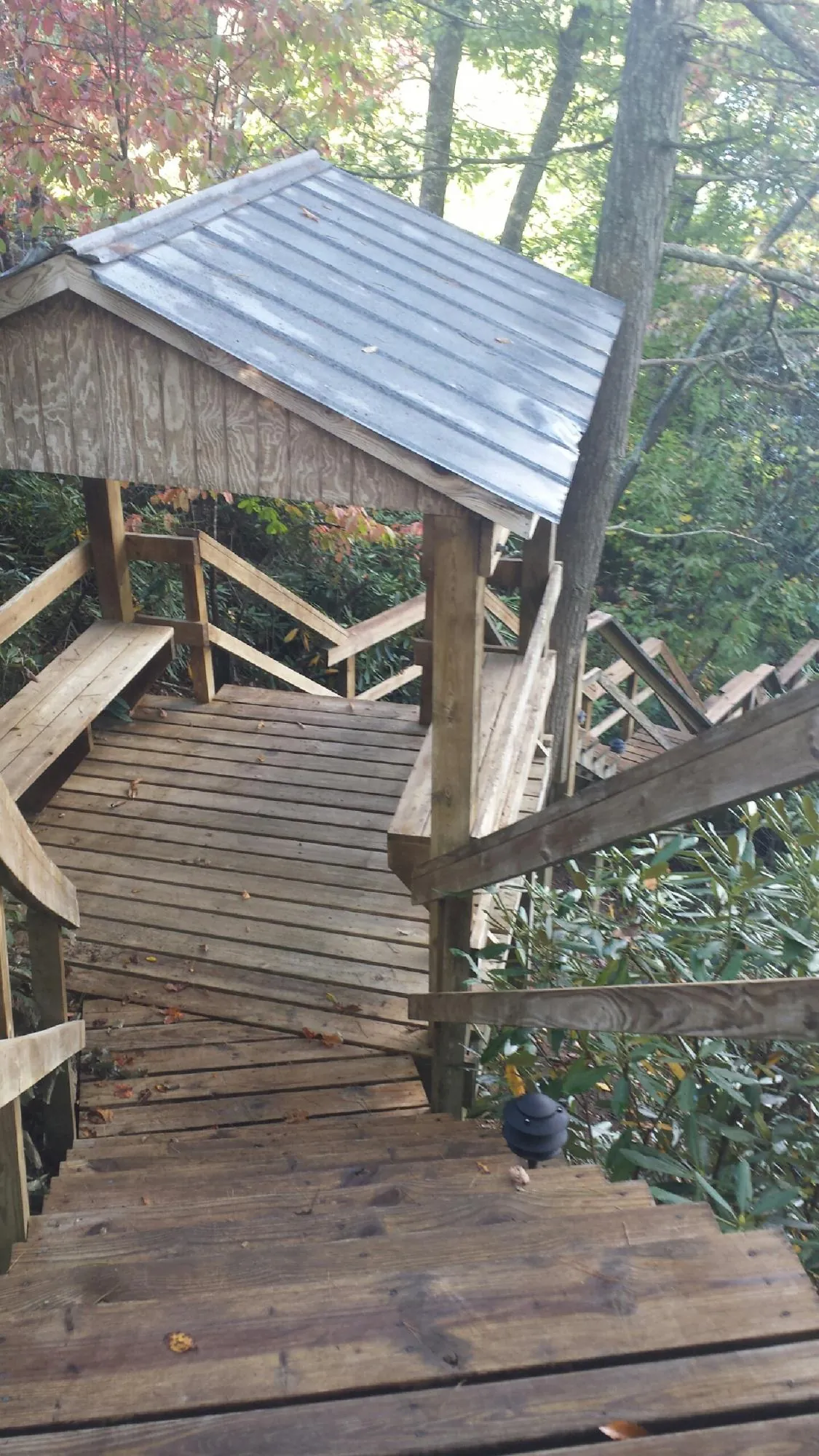 Metal roofed shelter over wooden steps on a wooded walkway — Skylight Repair & Installation work by our crew in Uhrichsville