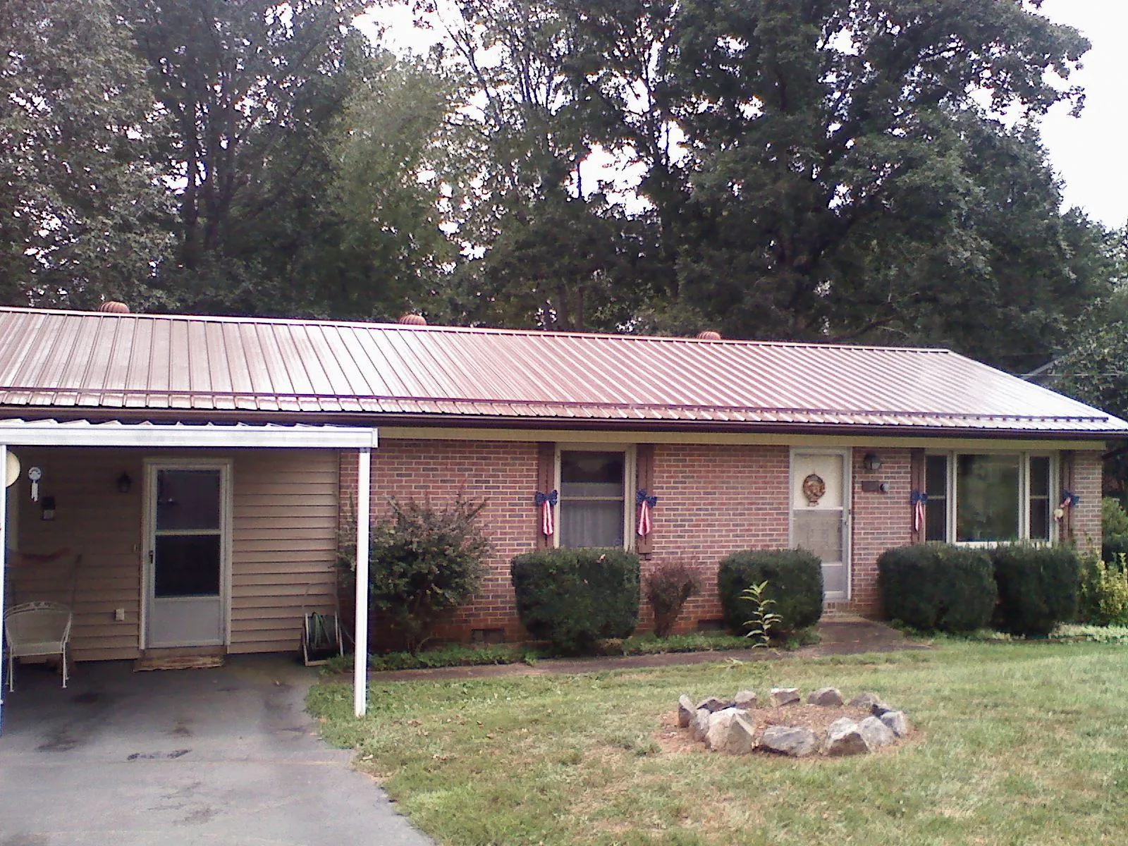 Bronze metal roof and carport on a brick ranch home — Roof Repair work by our crew in Uhrichsville