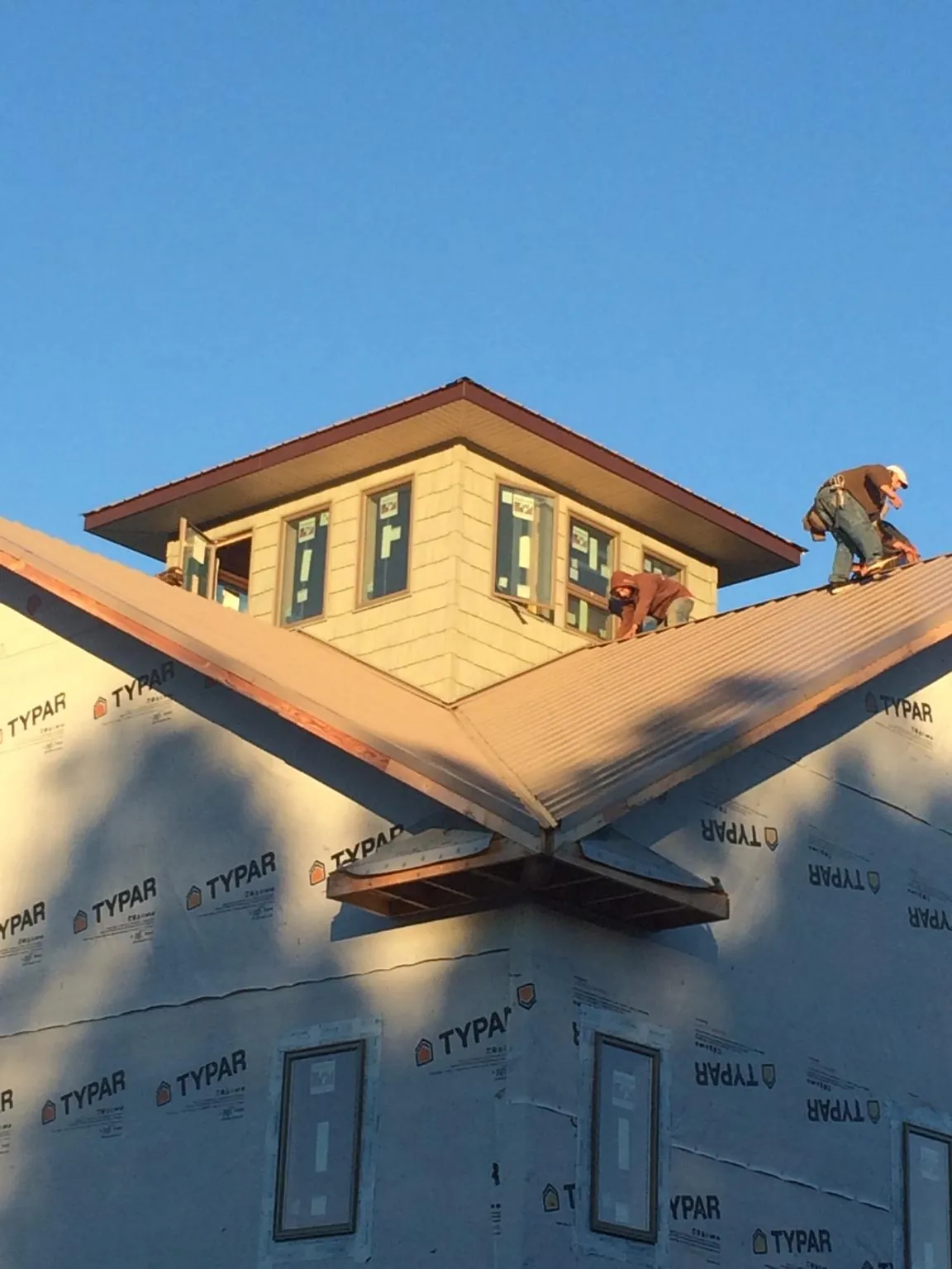 Roofers working around a rooftop cupola on a new metal roof at sunset — Roof Waterproofing in Uhrichsville by Roofing Brothers